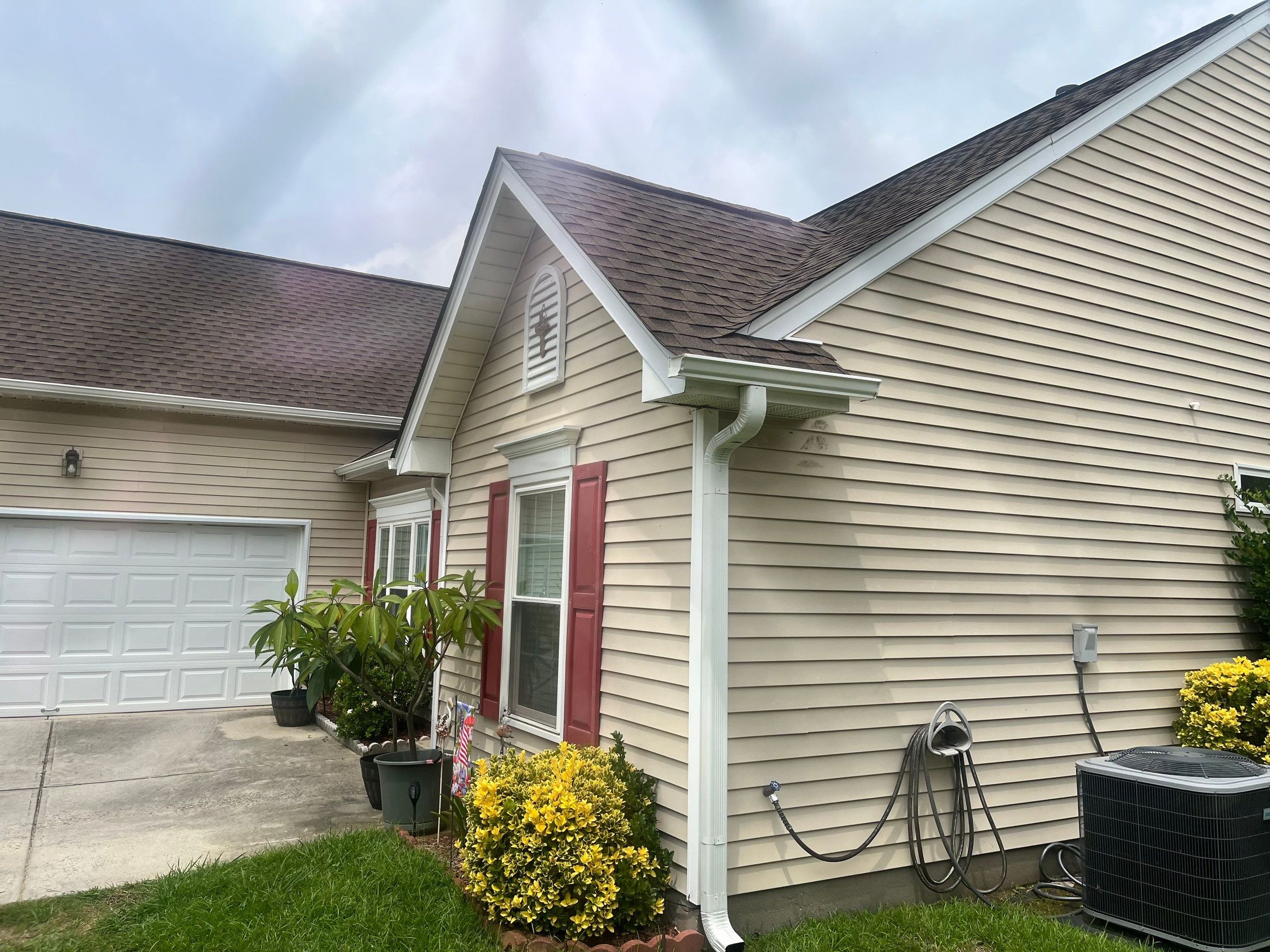 Roofline detail with new shingles, white fascia and a new white gutter and downspout