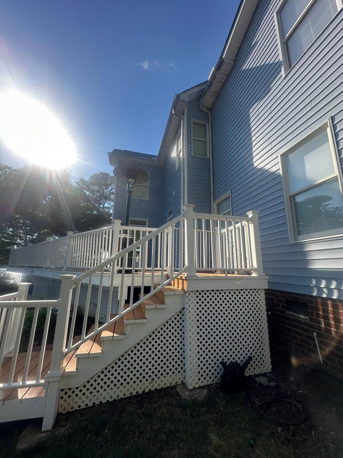 New white gutters and downspouts on deck stairs after a siding replacement in Mooresville
